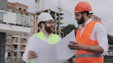 Mimar uzman mühendisleri konuşan ve tasarım planı inşaat alanında ayakta analiz. Meslekler, inşaat, işçiler, mimar konsepti. Yavaş hareket.