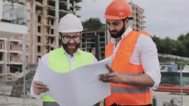 Bir konut kompleksi veya iş merkezi inşa. Mühendis erkek ekibi planları inşaat üreticileri iş aktivitesi analiz. Uzmanlar İnşaat planı memnun.