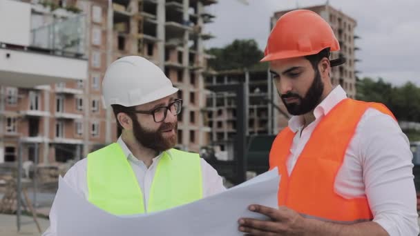 Arquiteto engenheiros especializados falando e analisar plano de design em pé sob canteiro de obras. Profissões, construção, trabalhadores, conceito de arquiteto. Movimento lento . — Vídeo de Stock