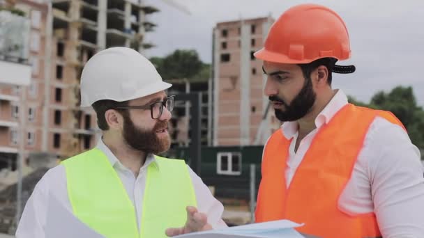 Construyendo un complejo residencial o centro de negocios. Equipo de ingenieros hombres analizan planes constructores actividad laboral. Los expertos están satisfechos con el plan de construcción . — Vídeos de Stock