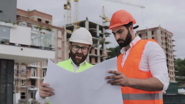 Arquiteto engenheiros especializados falando e analisar plano de design em pé sob canteiro de obras. Profissões, construção, trabalhadores, conceito de arquiteto. Movimento lento . — Vídeo de Stock