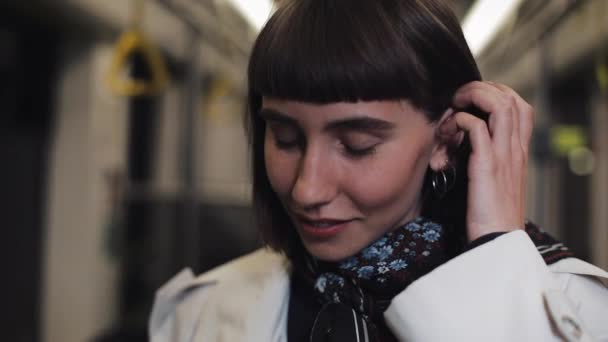 Όμορφη νεαρή γυναίκα κοιτάζοντας την κάμερα στο τραμ, φτιάχνοντας μαλλιά και χαμογελαστή, σταθερά shot. Γκρο πλαν. — Αρχείο Βίντεο