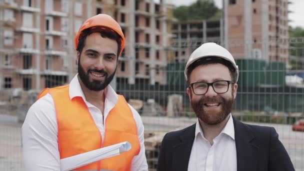 Porträt des glücklichen Bauunternehmers und Geschäftsmannes, der in die Kamera blickt, die im Hintergrund der Baustelle steht. Berufe, Baugewerbe, Arbeiter, Architektenkonzept. — Stockvideo