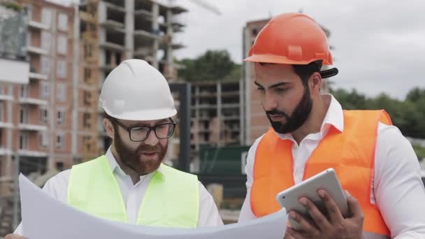 Building a residential complex or business center. Team of engineers men with a tablet and drawing analyzing plans construction builders job activity.