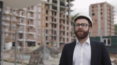 İş kıyafeti giyen yakışıklı mimar adam inşaat yerinde yürüyor. Meslek konsepti.