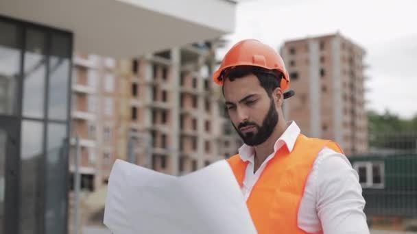 Építész ember sétál az építkezésen és elemző rendszer projekt terv. Kívül, lassított. — Stock videók
