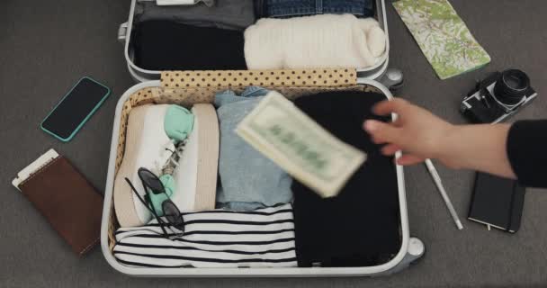 スーツケースにお金とパスポートを投げるクローズアップ。トップビューパッキングスーツケース. — ストック動画