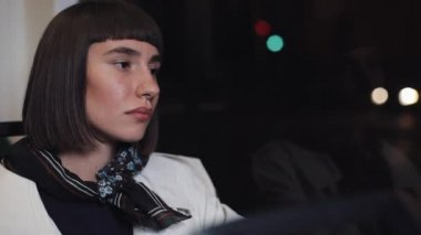 Toplu taşıma penceresinden dışarı bakan üzgün genç bir kadın. Yorgun kız pencerenin yanında oturan bir şey düşünüyor. Şehir ışıkları arka plan. Depresif kavram.