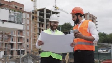 Bir konut kompleksi veya iş merkezi inşa. Bir tablet ve çizim analiz planlar inşaat üreticileri iş aktivitesi ile mühendis erkekler ekibi.