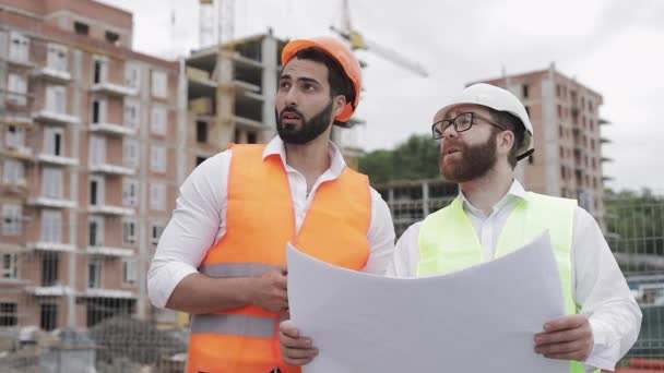 Der Bauherr und Architekt auf der Baustelle fotografiert mit dem Handy und überprüft mit dem Bauplan. — Stockvideo