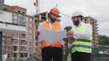 Bir konut kompleksi veya iş merkezi inşa. Bir tablet ve çizim analiz planlar inşaat üreticileri iş aktivitesi ile mühendis erkekler ekibi.