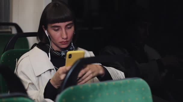 Retrato de mujer joven y elegante en auriculares escuchando música y navegando en el teléfono móvil en el transporte público. Joven mujer de negocios profesional urbana exitosa que recibe buenas noticias . — Vídeos de Stock