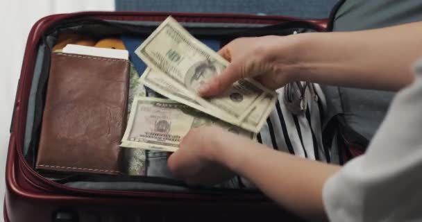 Peníze na cestování. Ženská ruka počítá dolarové bankovky na pozadí kufru. Holka jede na cestě. Kufr s věcmi. — Stock video