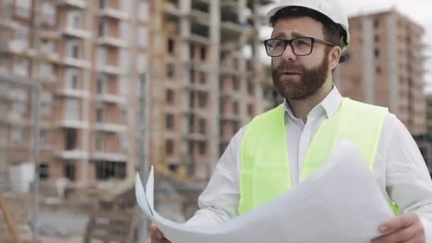 Arkitekt man gå på byggarbetsplatsen och analysera schema projektplan. Utanför, slow motion. — Stockvideo