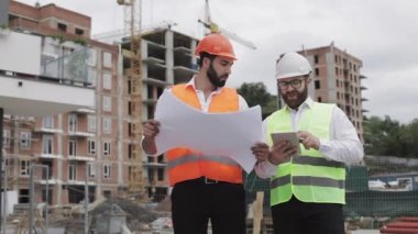 Bir konut kompleksi veya iş merkezi inşa. Bir tablet ve çizim analiz planlar inşaat üreticileri iş aktivitesi ile mühendis erkekler ekibi.