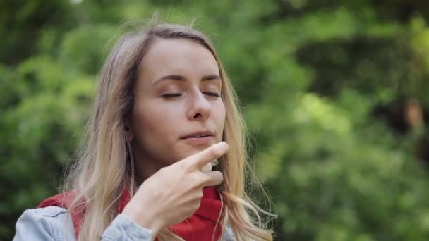 公園の背景に立って喉のスプレーを使用して若い女性.健康と医療の概念. — ストック動画