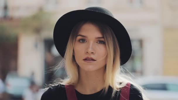 Portrait of Young Blond Girl With Piercing in the Nose Wearing a Black Hat Turning Head to Camera Standing on the City Street Close Up. — Stock Video