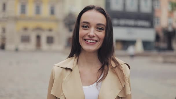 Porträt einer schönen jungen Dame, die glücklich und entspannt lächelnd und lachend am Hintergrund der Stadt steht, aus nächster Nähe. — Stockvideo