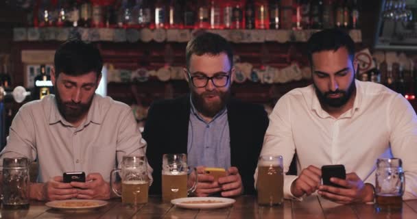 Trois vieux amis utilisant des smartphones assis dans le pub de la bière. Communication, concept de dépendance à Internet . — Video