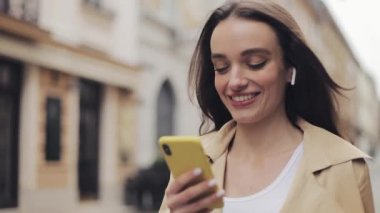 Sokakta Yürüyen Kulaklık Takan Genç Gülümseyen Güzel Beyaz KızA YakınLaşma Kelebiye Telefonu Elinde Tutup Yazarak.