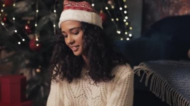 Noel Baba Şapkalı Güzel Mulatto Kızının Kapanışı Dekoratif Noel Ağacı Hazırlama Hediyeleri, Paketleme Hediyeleri Altında Oturuyor. Bayram Kutlama Konsepti.