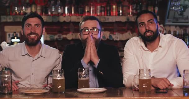 Tres viejos amigos bebiendo cerveza, animando juntos en un pub. Futbolistas, amistad, concepto deportivo . — Vídeo de stock