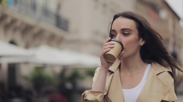 Mooi jong meisje Holding papier beker drinken cofee glimlachen wandelen ontspannen op stad achtergrond close-up. — Stockvideo