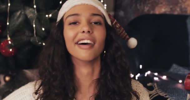 Okouzlující šťastná žena v klobouku Santas s videohovory, ukazuje současné krabice na kameru, usmívá se, zatímco sedí u vánočního stromku. Komunikace a vánoční dovolená koncepce. — Stock video