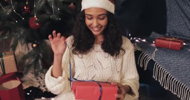 Mulher Sorridente Atraente Sentado sob Árvore de Natal no Cosy Home Background enquanto abre Red Present Box, Looking Satisfied with her Present. Conceito de celebração de Natal e Ano Novo . — Vídeo de Stock