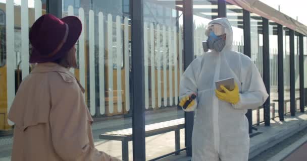 Junge Reisende mit Fieber bei Temperaturkontrolle am Bahnhof. Mediziner in Schutzanzügen mit Tablette und Screening-Beifahrer. Konzept der Covid-Epidemie. — Stockvideo