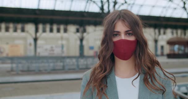 Vista da vicino della ragazza adulta in maschera protettiva fatta a mano cercando di fotocamera. Ritratto di giovane donna bruna seria in piedi da sola. All'aperto. Concetto di pandemia virale . — Video Stock