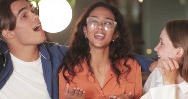 Kahvede iyi vakit geçirirken gülen ve konuşan neşeli genç arkadaşların kırsal manzarası. Çok ırklı insanlarla iletişim kuran bir grup. Arkadaşlık kavramı ve olumlu duygular.