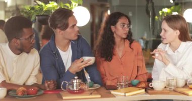 Modern kafede iş arkadaşlarıyla düşüncelerini paylaşan bin yıllık atraktif bir kız. Çok ırklı başarılı gençler bayan meslektaşlarını dinliyor. İletişim kavramı.