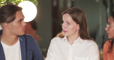 Modern kafede konuşurken eğlenen neşeli çoklu etnik arkadaşlara yakın durun. Milenyum gülümseyen iş arkadaşları öğle yemeği sırasında sohbet ediyorlar. Dışarıda yemek yeme kavramı.