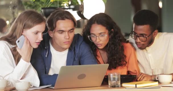 Vista Crop di colleghi millenari rendendo volto stupito mentre guardando lo schermo del computer portatile. Giovani startupers sorpreso avendo buone notizie mentre seduto in caffè. Concetto di successo e lavoro di squadra — Video Stock