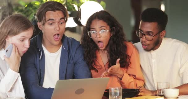 Jonge collega 's die verrast kijken terwijl ze naar het laptopscherm kijken. Millennial verbaasd startupers met goed nieuws tijdens het zitten in cafe. Concept van succes en teamwork. — Stockvideo
