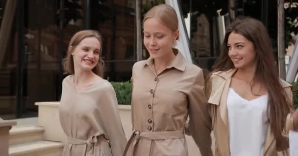 Millennial cheerful girls hugging and smiling while carrying paper bags. Three beautiful women having good mood while walking at city street after shopping. Concept of friendship. — Stock Video