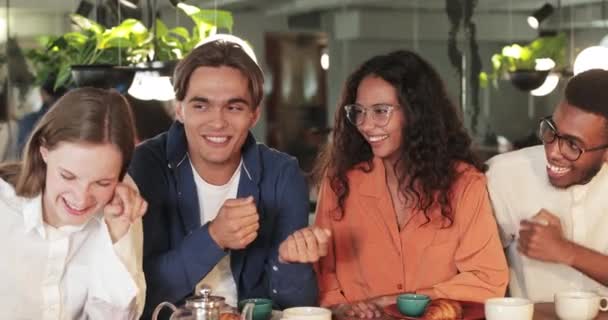 Crop view jovem caucasiano alegre homem gesticulando e falando enquanto sentado com amigos multiétnicos no café. Jovens alegres ouvindo e rindo. Conceito de comunicação . — Vídeo de Stock