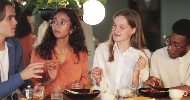 Young cheerful friends having fun and laughing while eating in modern cafe. Millennial people talking and enjoying leisure time. Concept of friendship and happiness . — Stock Video