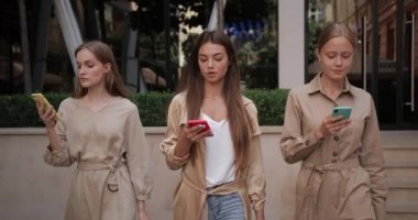 Genç çekici kızlar sokakta kese kağıdıyla yürürken modern akıllı telefonlarını kullanıyorlar. Milenyum kadını, arkadaşının telefon ekranına bakarken yüz ifadesine hayran kalıyor..