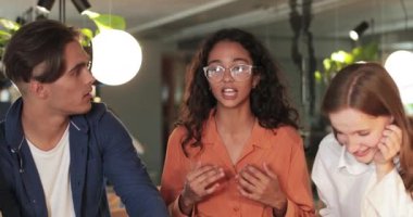 Modern kafedeki arkadaşlarına komik bir hikaye anlatırken gözlüklü çekici bir kadın manzarası. Neşeli gençler sohbet ediyor ve gülüyorlar. İletişim kavramı.