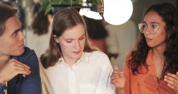 Vue sur la récolte de joyeux amis multi-ethniques communiquant et souriant tout en mangeant dans un café confortable. Débutants millénaires bavarder et profiter du temps libre. Concept de style de vie.