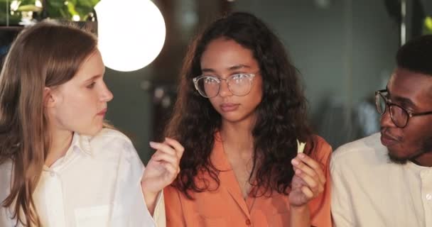 Vue rapprochée des jeunes qui communiquent en mangeant pendant le déjeuner dans un café moderne. Amis millénaires parler et profiter du temps libre. Concept d'amitié et manger dehors.