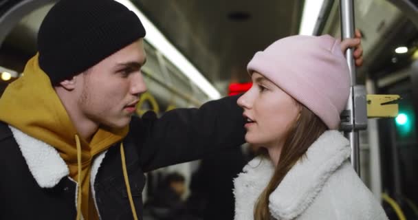 Pareja joven charlando y mirándose. Millennial chico y chica sonriendo y hablando mientras va en transporte público. Concepto de comunicación . — Vídeo de stock