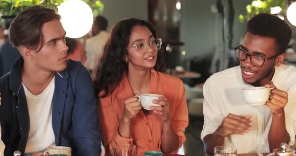 Close up of multiethnic friends drinking tea and talking while having lunch. Happy young students chatting and having good time while sitting in cosy restaurant. Concept of communication. — Stock Video