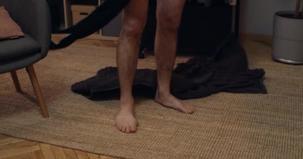 Вид чоловічої особи, що знімає рушник для ванни і кладе чорні колготки на ногу, стоячи. Домашній фон . — стокове відео