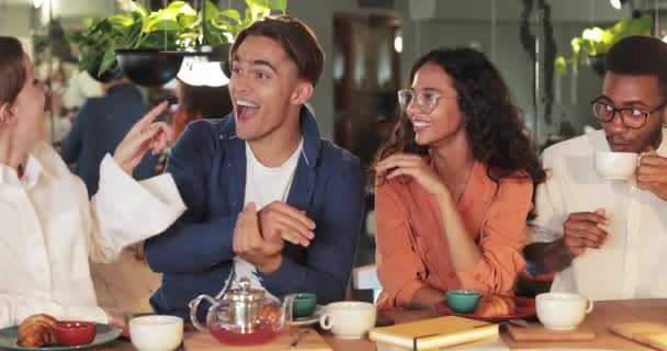 Happy young people gesturing and talking while spending good time together. Cheerful friends laughing and chatting while having meal in cosy restaurant. Concept of positive emotions. — Stock Video