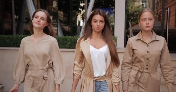 Beautiful young girls in trendy clothes carrying paper bags while walking at city street. Good looking female friends holding their purchases after shopping. Concept of fashion. — Stock Video