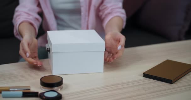 近距离观察女性的手打开包装礼物.女人站在桌子上,桌上挂着化妆品的开著的白色盒子的剪影.美的概念. — 图库视频影像