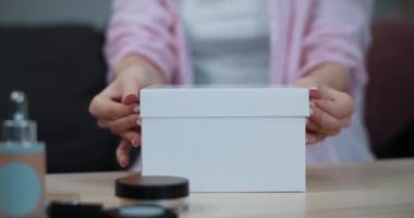 Bayan ellerinin bavullarını açarken yakın görüntüsü. Üzerinde kozmetik ürünler olan beyaz bir kutunun üzerinde duran kızın kırpma görüntüsü. Güzellik kavramı.